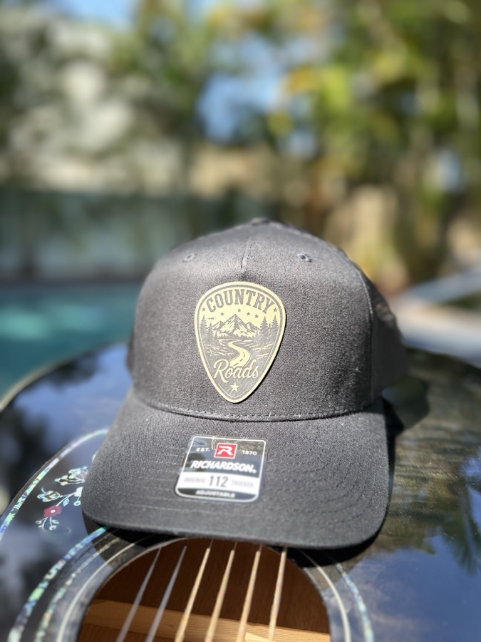 Country Roads black Richardson 112 hat with a laser-engraved leather patch, styled on an acoustic guitar poolside