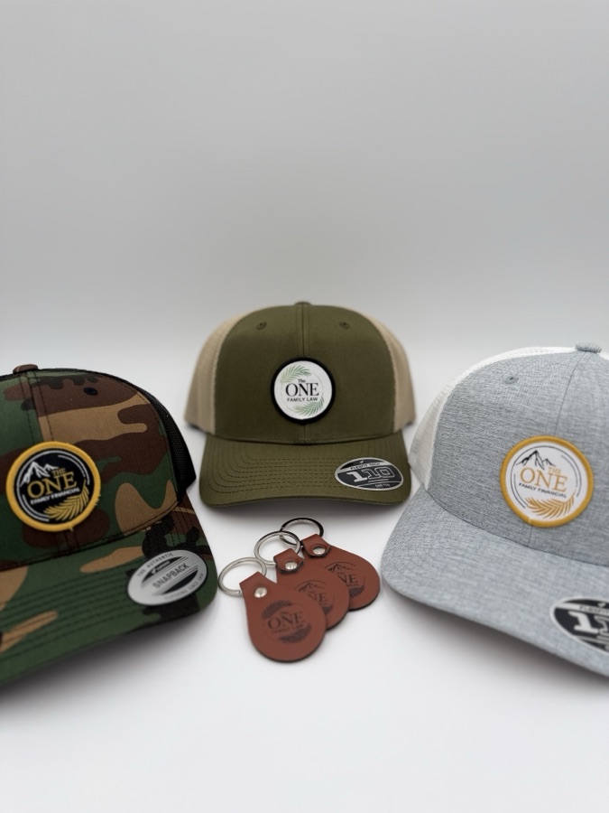 The One branded trucker hats with matching laser-engraved leather keychains