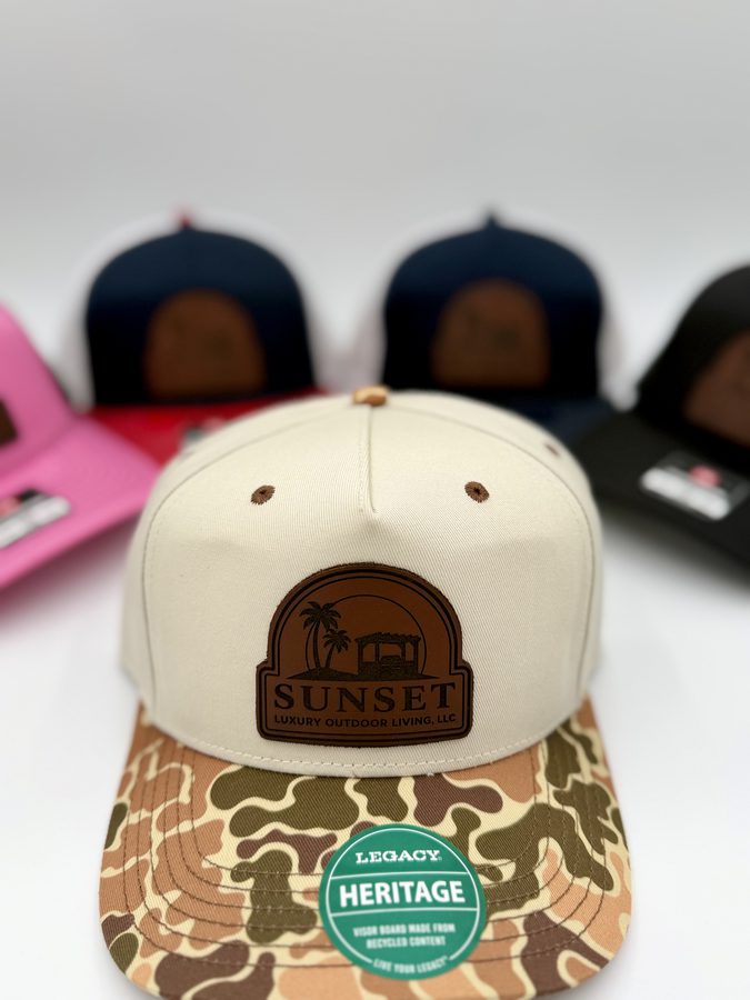 Sunset Luxury Outdoor Living cream rope cap with a duck-camo brim and an engraved leather patch