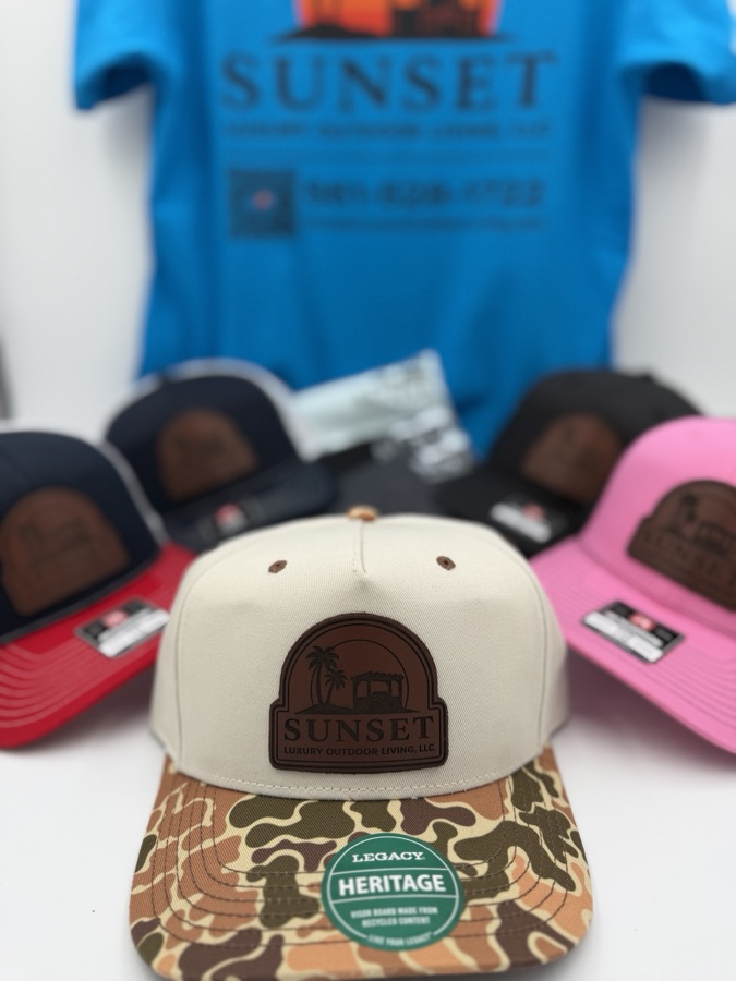 Sunset Luxury Outdoor Living hat lineup — laser-engraved leather patch trucker hats in multiple colorways with a matching branded tee
